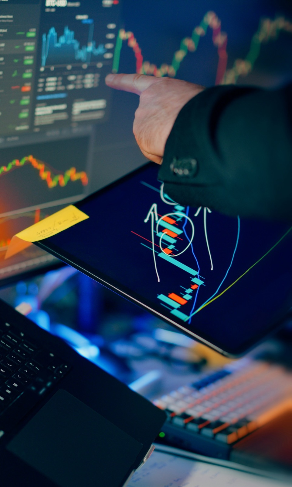 Trader reviewing market charts across a screen and tablet