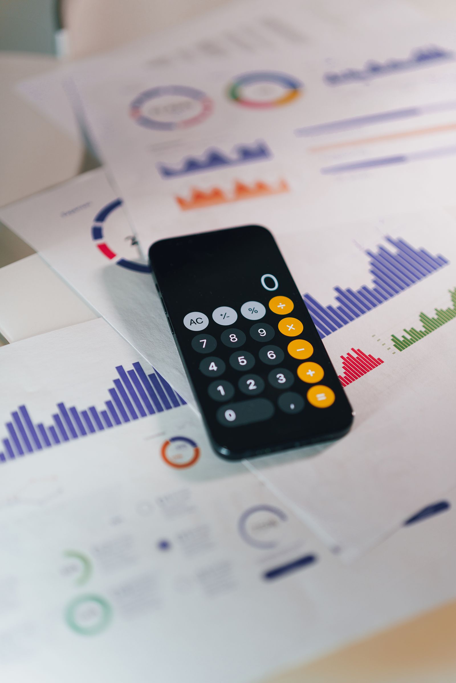 Real calculator placed over printed financial charts and reports